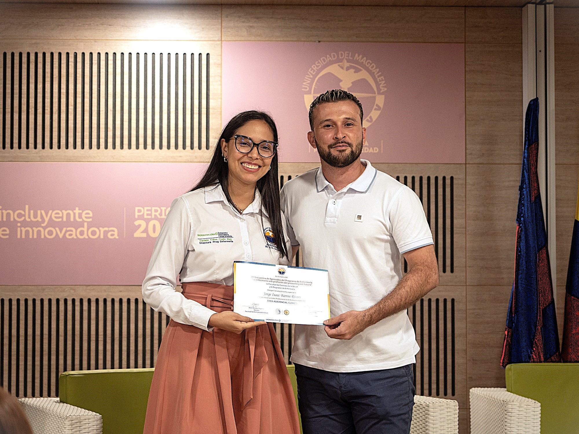 Daniela Trillos Cuello, directora del Programa de Enfermería, entregando el reconocimiento a Jorge Barros Rivera.
