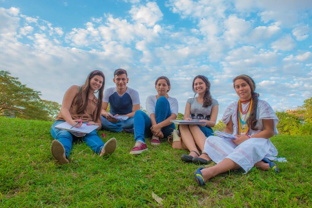 Imagen de presentación para las unidades académicas donde aparecen estudiantes sentados en al zona del lago.